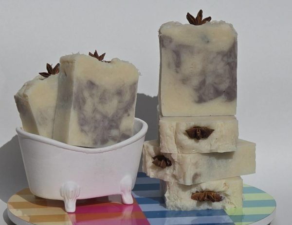 A stack of chichaito soap bars on a table next to a bathtub.`