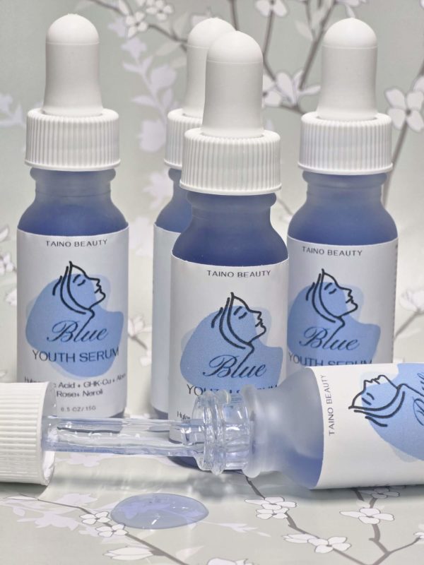A group of five blue glass bottles with white dropper caps, labeled Blue Youth Serum